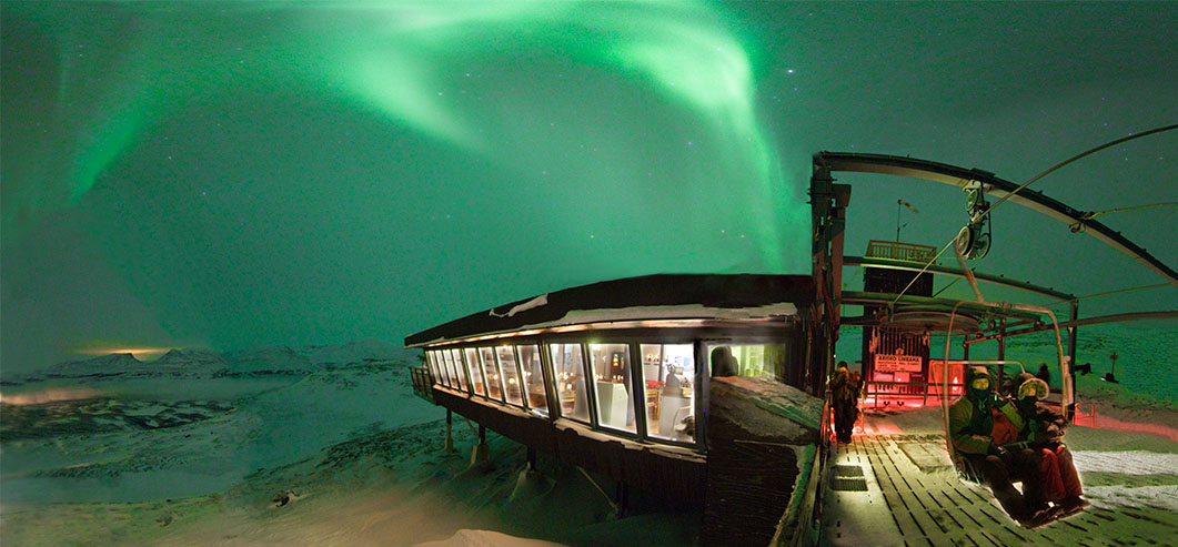 Aurora Sky Station building on a mountain ridge beneath northern lights