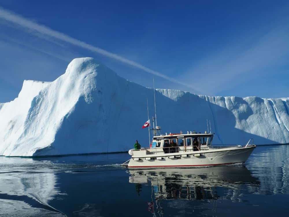 large iceberg with small boat infront