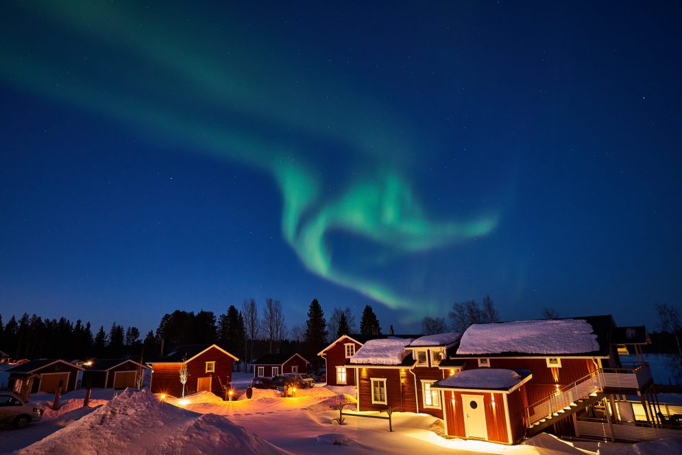 northern lights above red cabins