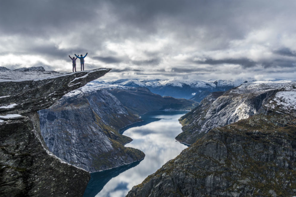 Trolltunga cliff viewpoint with a person standing on the rock above a fjord