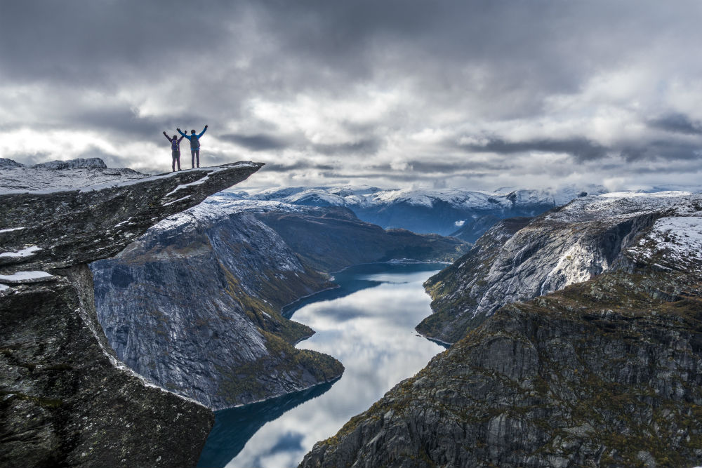 Trolltunga cliff viewpoint with a person standing on the rock above a fjord