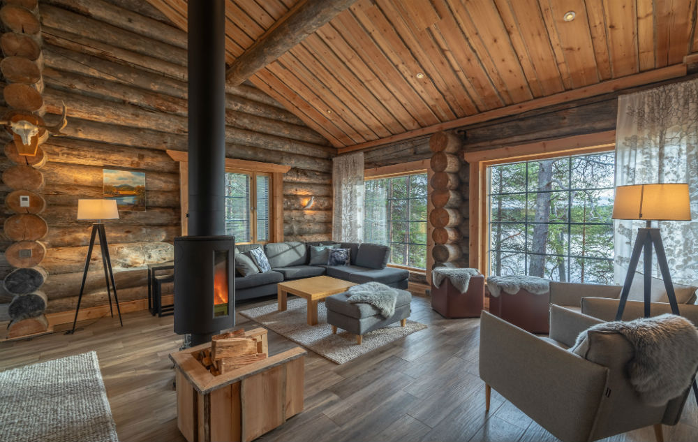inside log cabin with corner sofa, log burner and 2 large windows