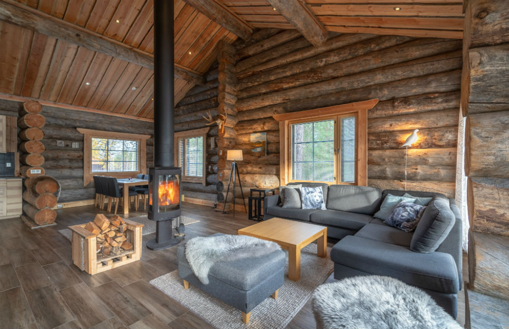 inside log cabin with corner sofa, log burner and 2 large windows