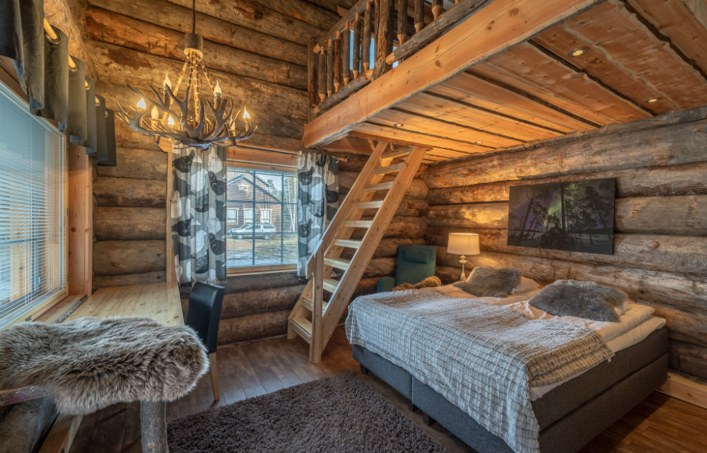 log cabin with double bed and stairs up to the loft