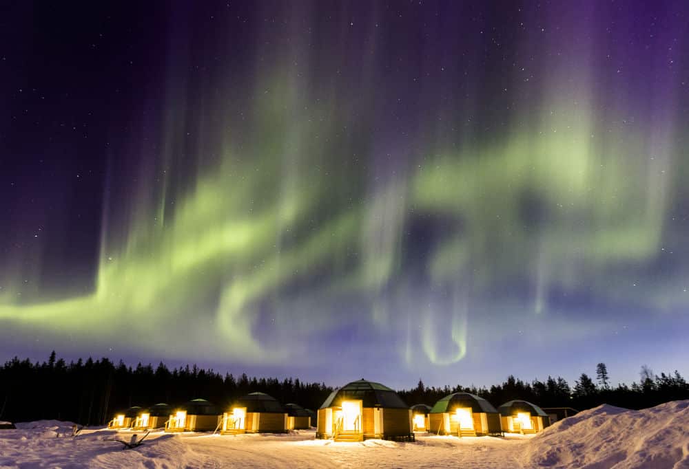 Glass igloos glowing at night in a snowy resort, lit from inside