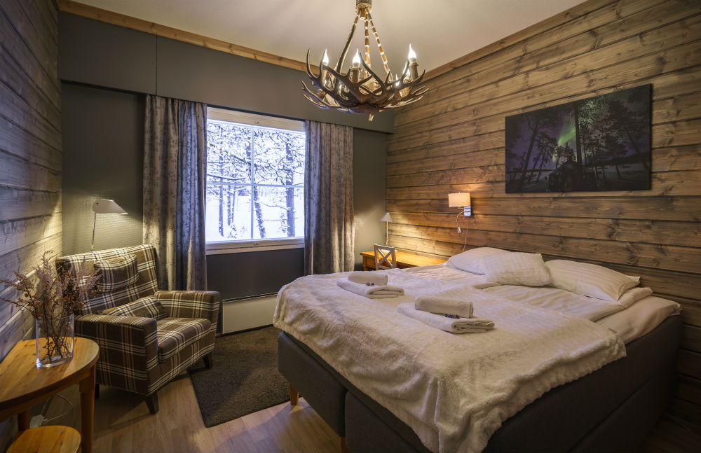 double bed with armchair in corner and picture of northern lights on the wall