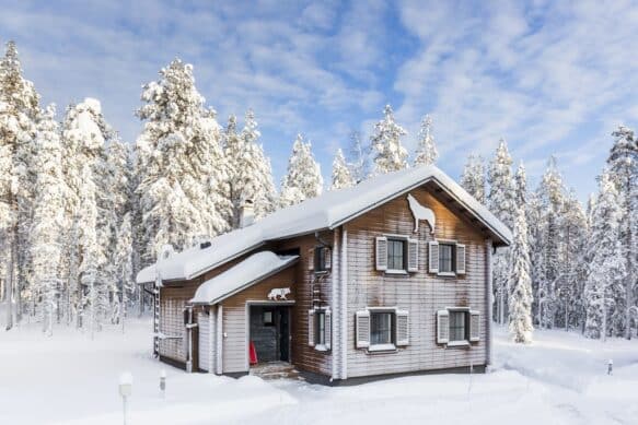 holiday villa covered in snow with the forest behind