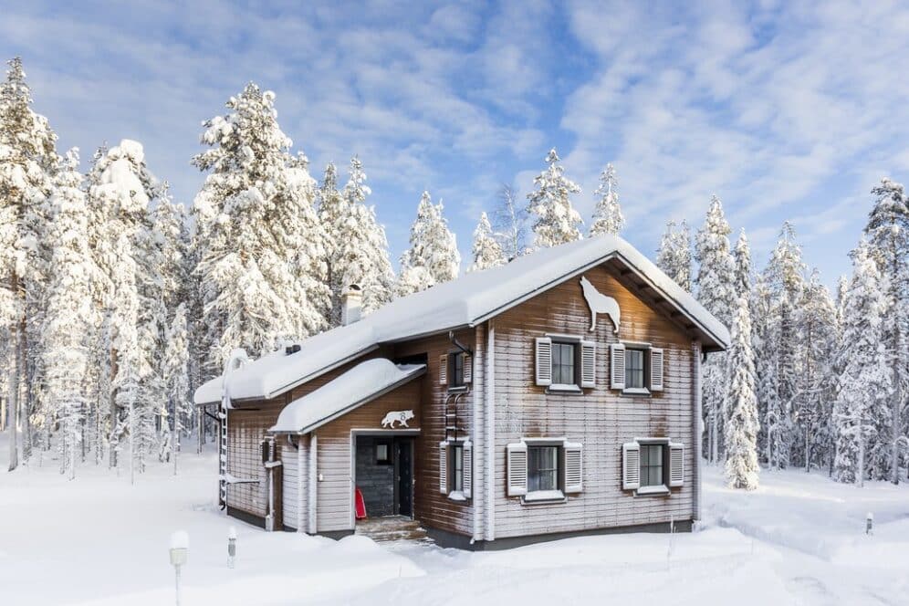 holiday villa covered in snow with the forest behind