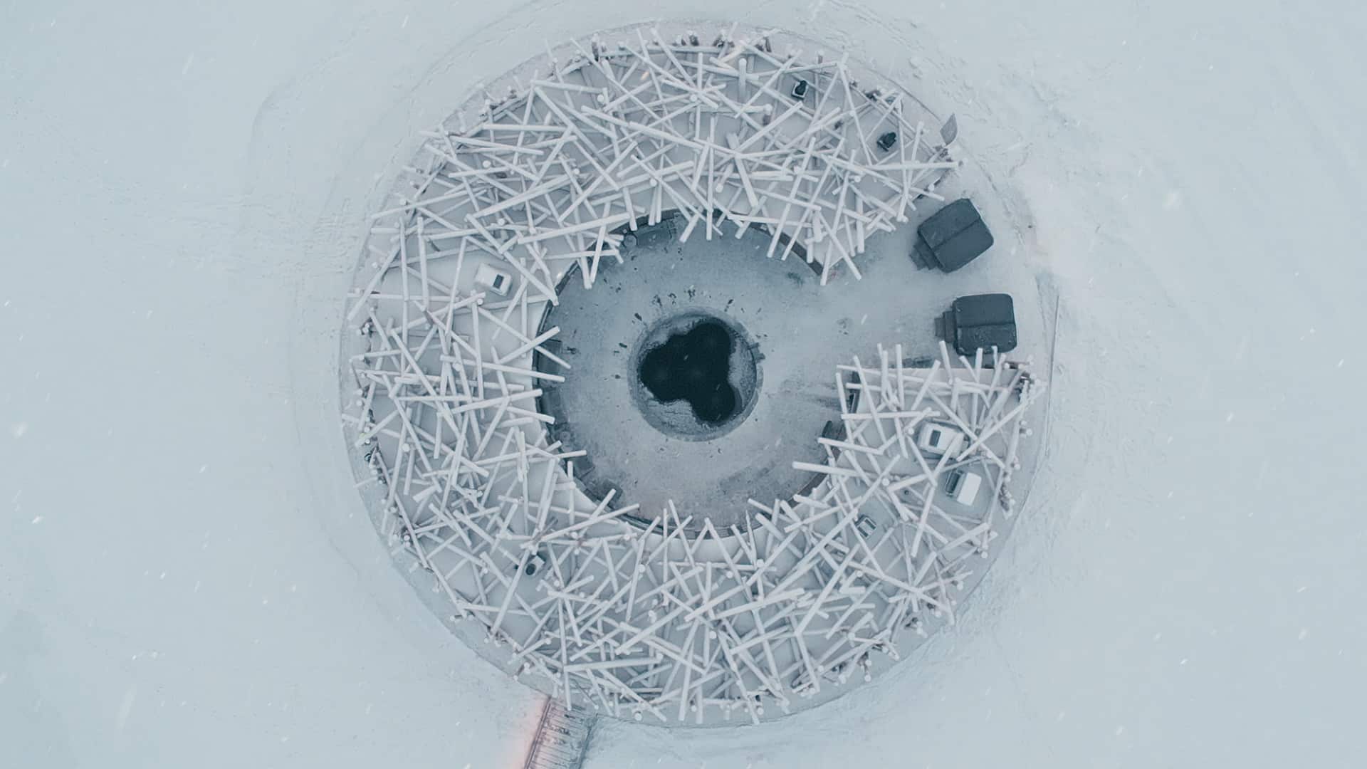 Aerial view of the circular Arctic Bath structure on a frozen river/lake