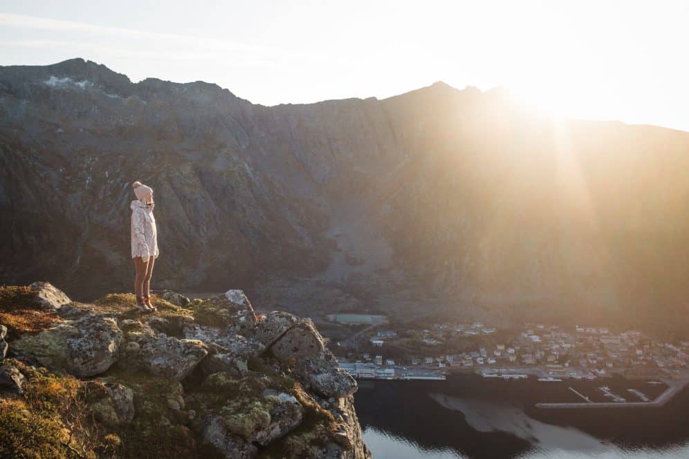 woman stood on mountain edge with sun coming over the mountains