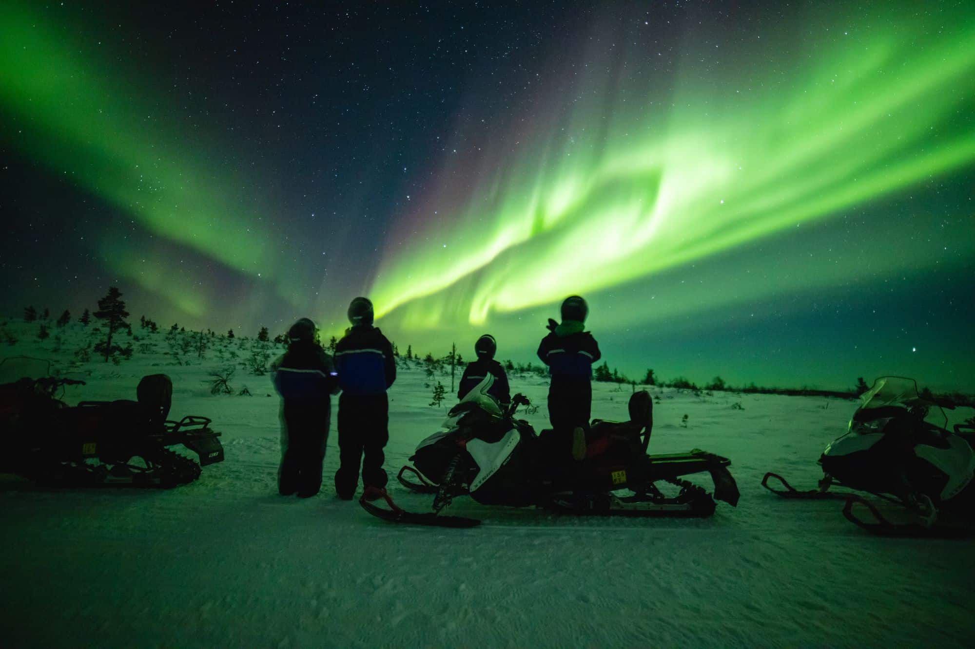 northern lights above snowmobiles