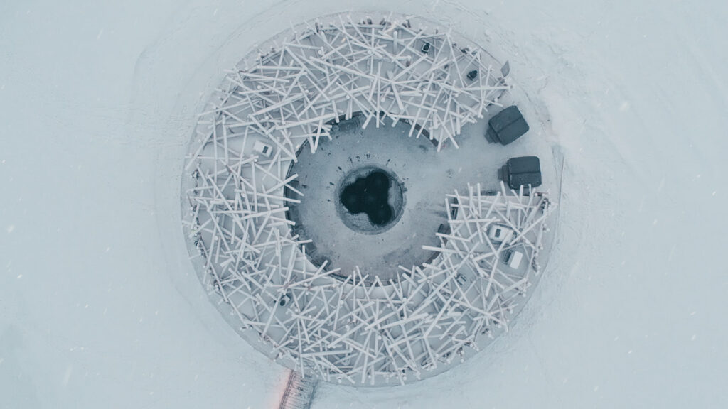Aerial view of the circular Arctic Bath structure on a frozen river/lake