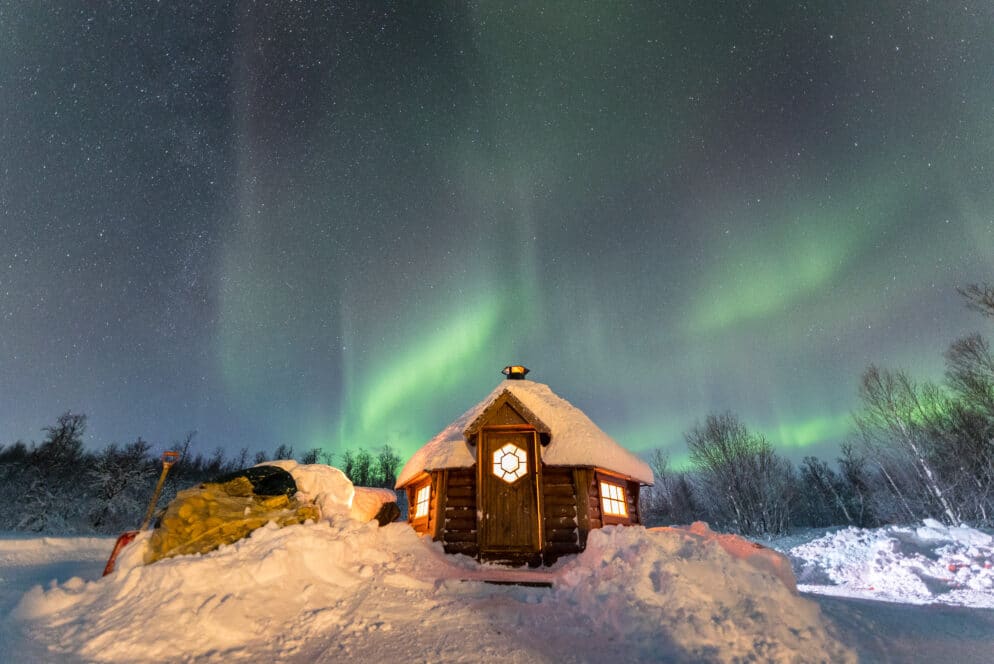 wooden hut with northern lights above