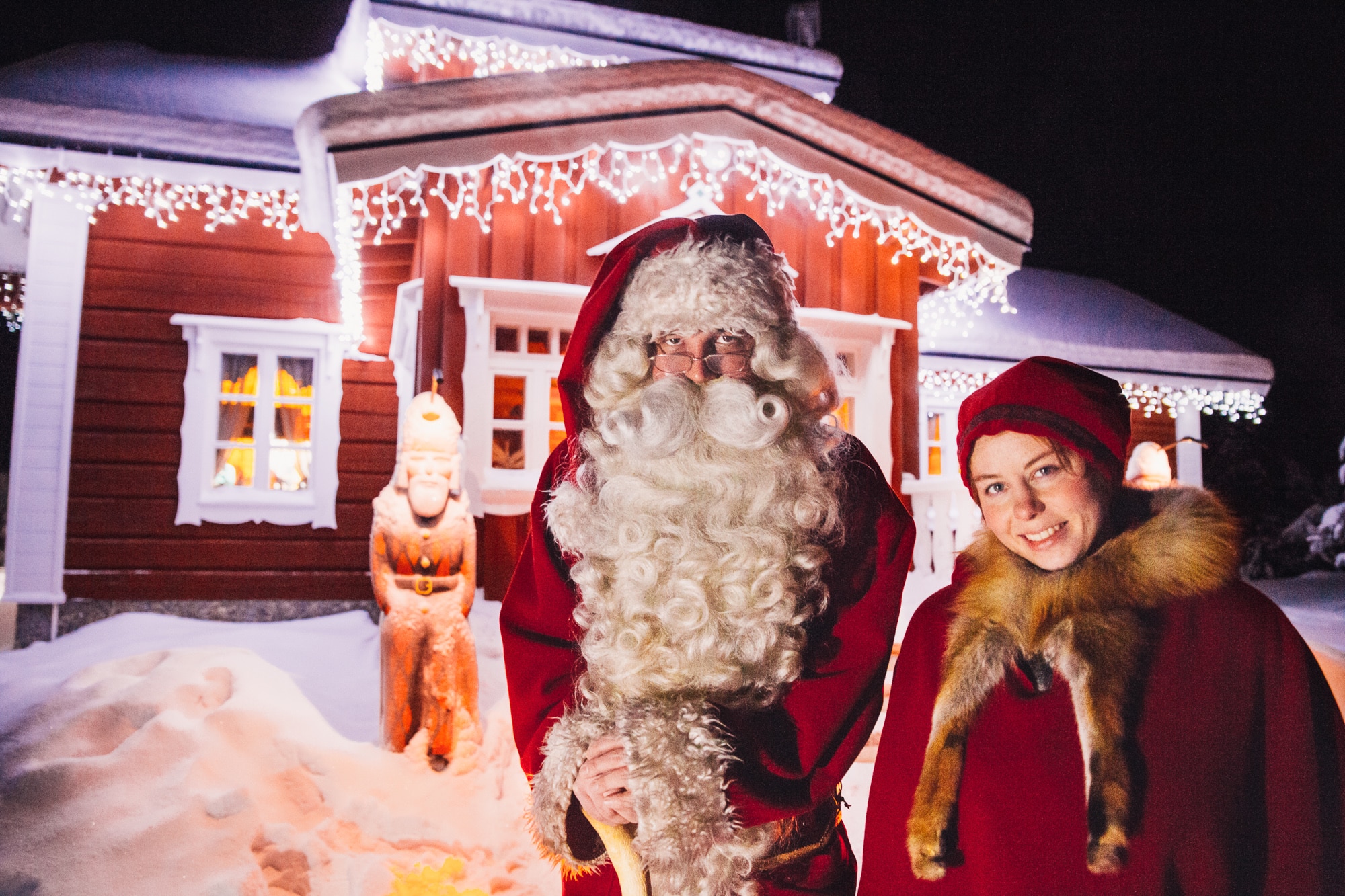 santa and elf stood outside cabin
