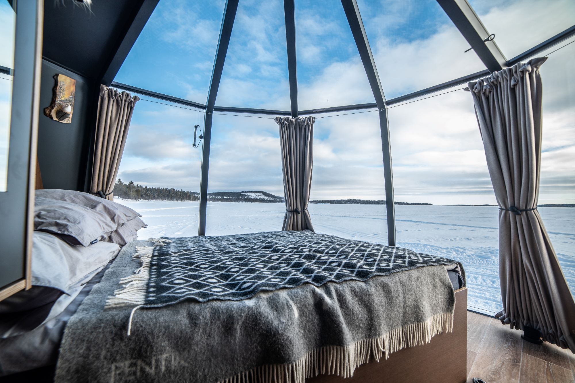 aurora hut inside with double bed and view of the snowy landscape