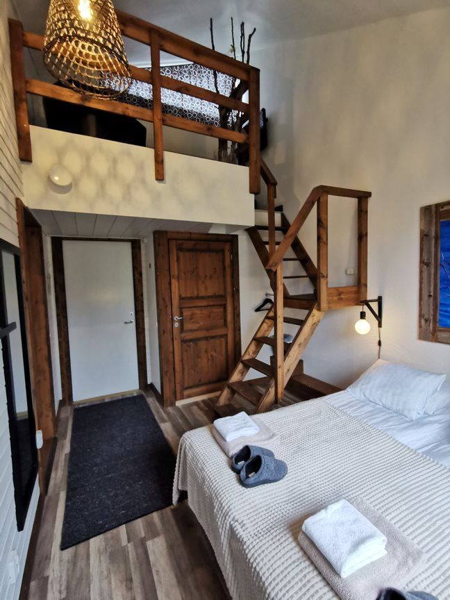Loft-style cabin bedroom with wooden stairs and a double bed under sloped ceiling