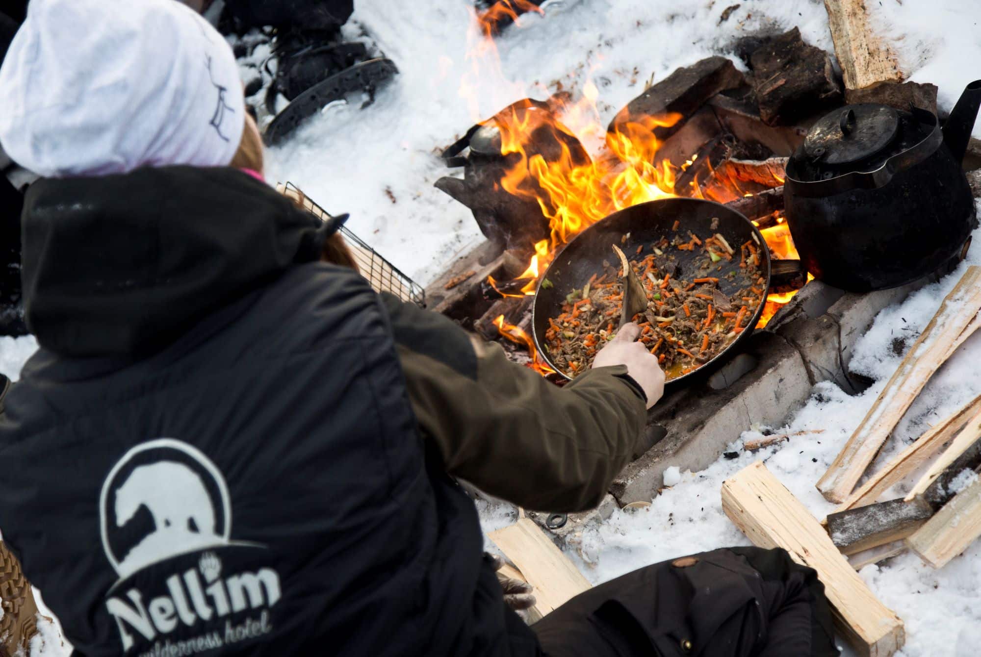 person cooking over camp fire in the snow