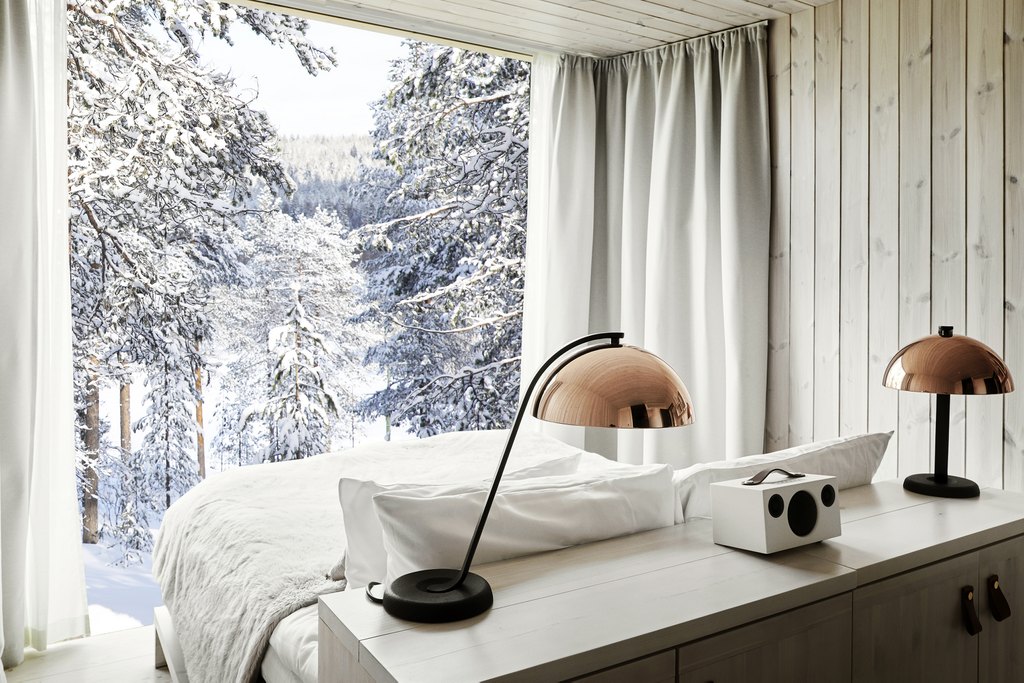 double bed facing a large window which overlooks the forest