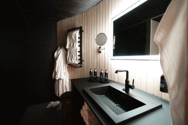 Modern bathroom with sink, mirror, towels and bathrobes in a spa-style setting