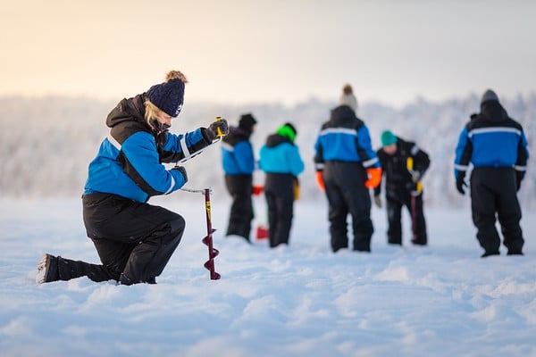 woman kneeling on the ice doing icefishing