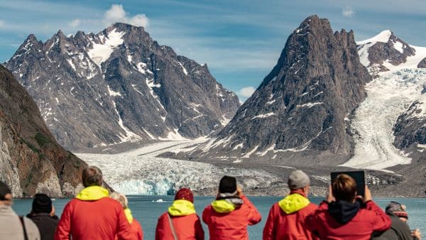 people taking photos of mountain range in greenland