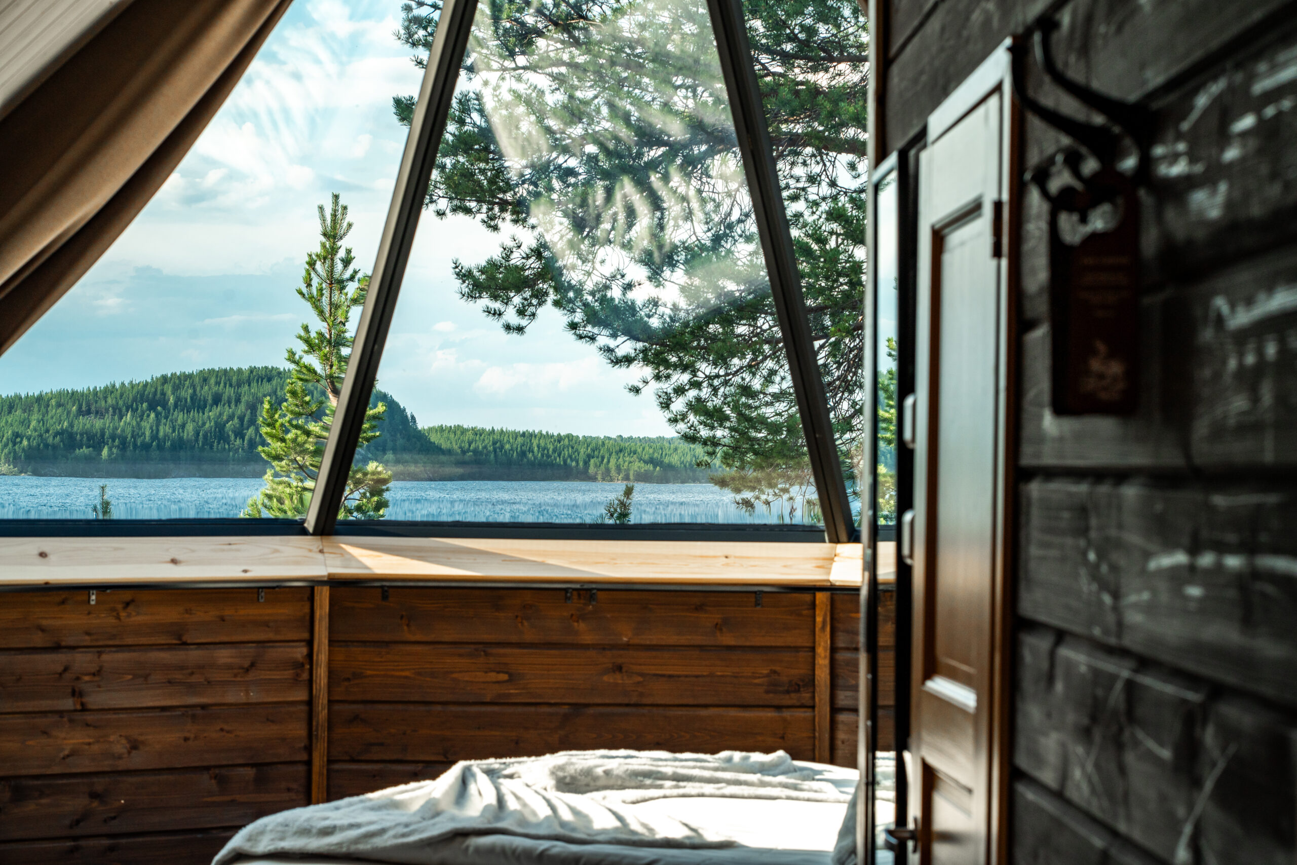 summer view of forest and river from inside glass igloo