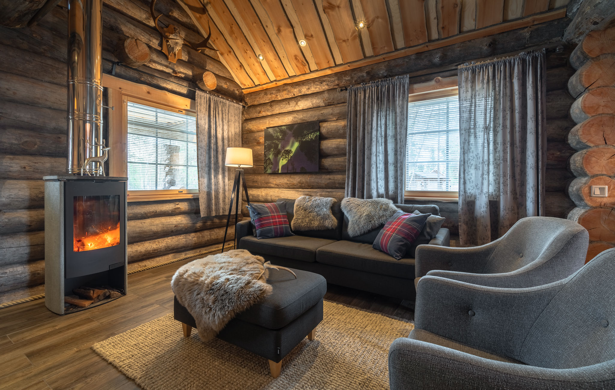 Cozy log cabin living room with fireplace, dining table and large windows