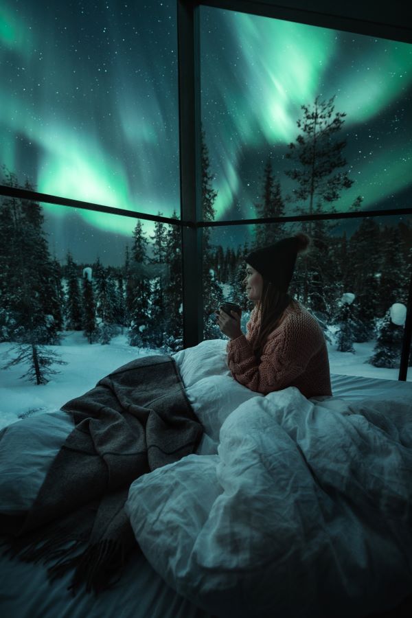 woman sat in bed watching northern lights