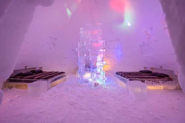 Ice hotel bedroom with ice beds decorated with snow sculptures