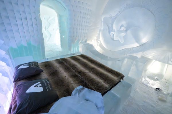 double bed made of ice in a snow room with wall carvings