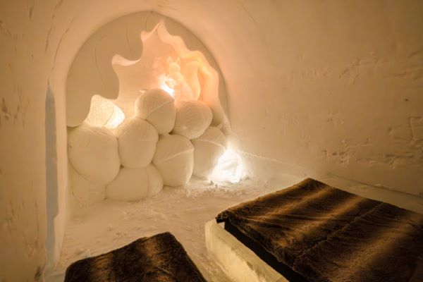 Ice hotel bedroom with ice beds decorated with snow sculptures