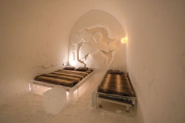 Ice hotel bedroom with ice beds decorated with snow sculptures