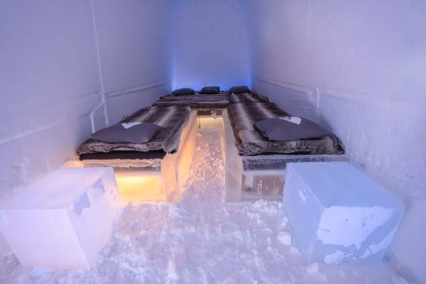 Ice hotel bedroom with ice beds decorated with snow sculptures