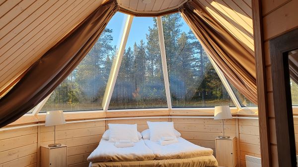 double bed in glass igloo overlooking trees