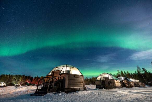 glass igloos with northern lights above