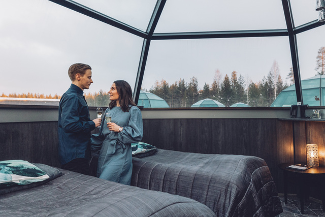 couple drinking champagne inside a glass igloo
