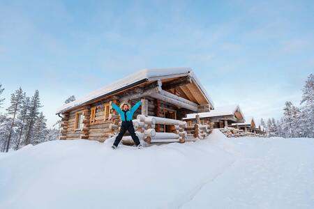 person in the snow infront of a cabin
