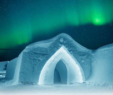 entrance to arctic snow hotel with northern lights above