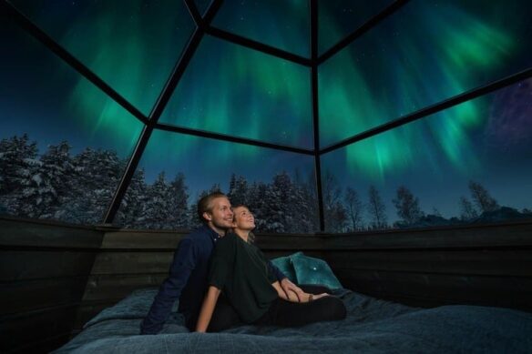 couple sat in igloo with northern lights above