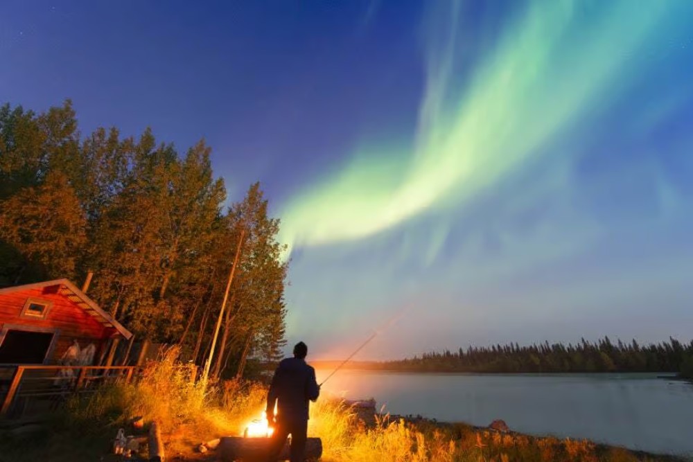 northern lights above a man fishing
