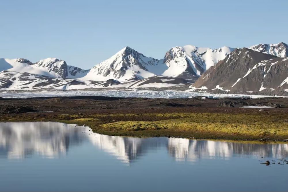 Colourful boats and cabins in a Spitsbergen fjord with mountains under summer light