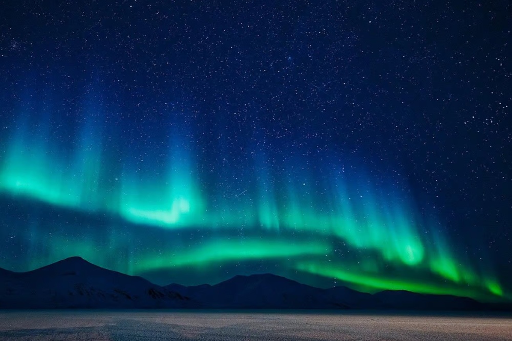 northern lights in svalbard above the mountains