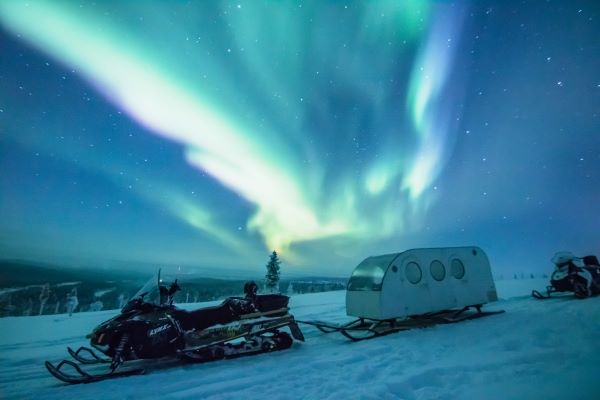 snowmobile with snowmobile sleigh under the northern lights