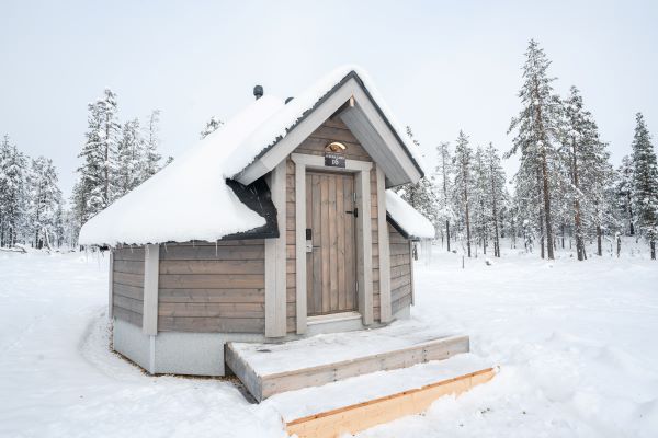 Small wooden cabin building surrounded by deep snow in winter