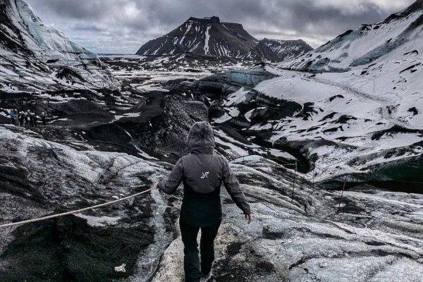 person climbing over rocky terrain in iceland