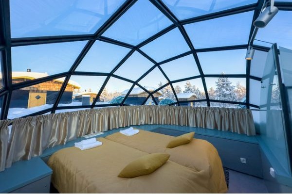 double bed inside glass igloo with winter forest scenery